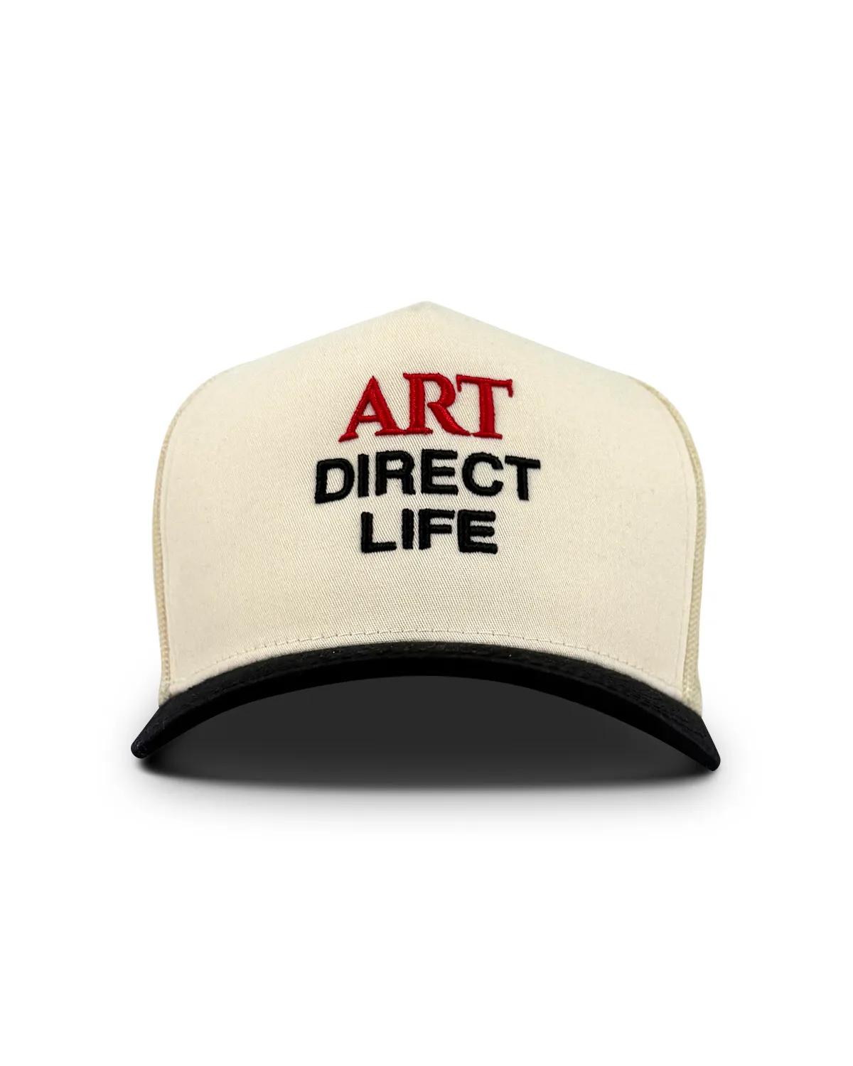 Cream crowned trucker cap with a black brim, front view, with ART embroidered in red above DIRECT LIFE in black