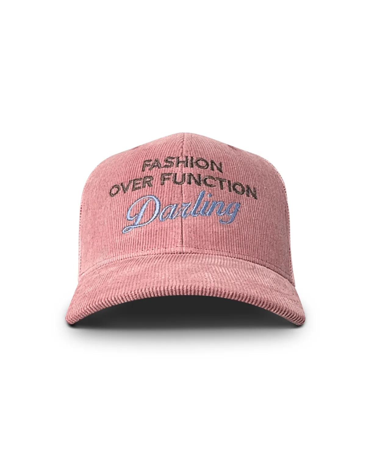 Pink corduroy trucker cap, front view, with FASHION OVER FUNCTION arched above Darling in pale blue script